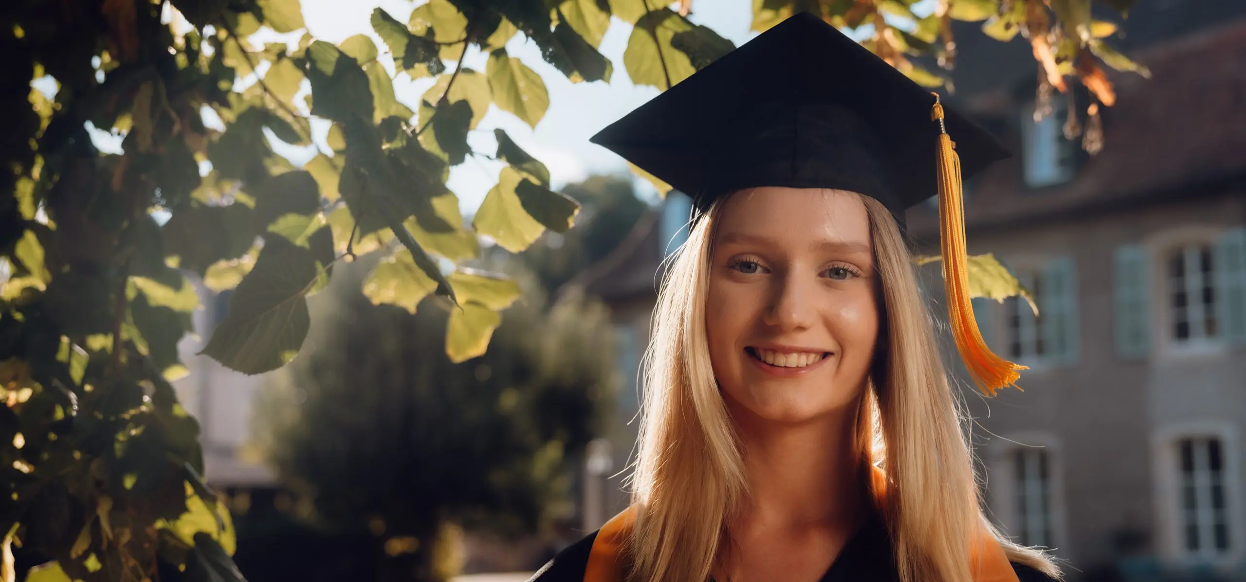 Student smiling wearing a graduate hat