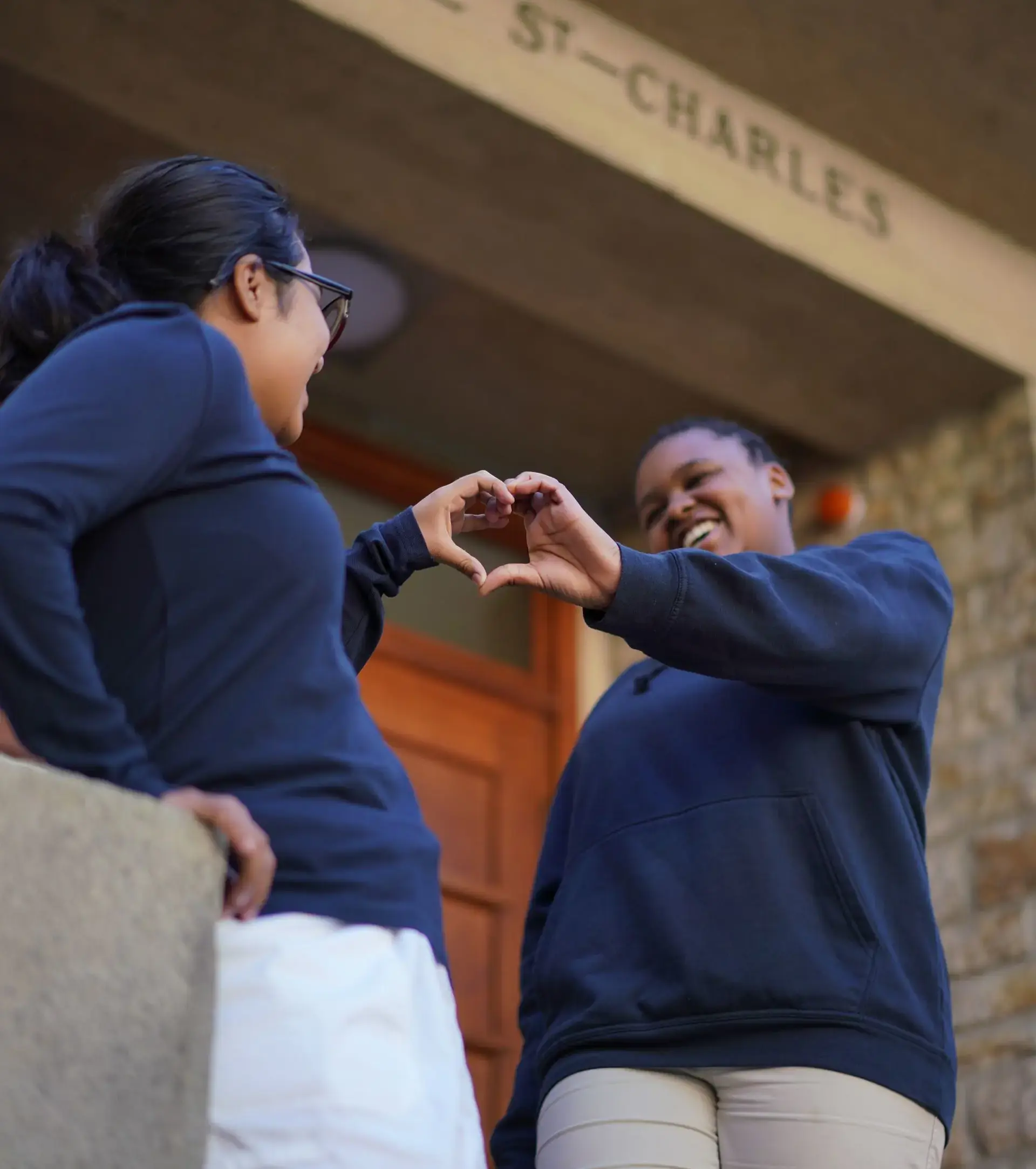 Two students making a heart with their hands