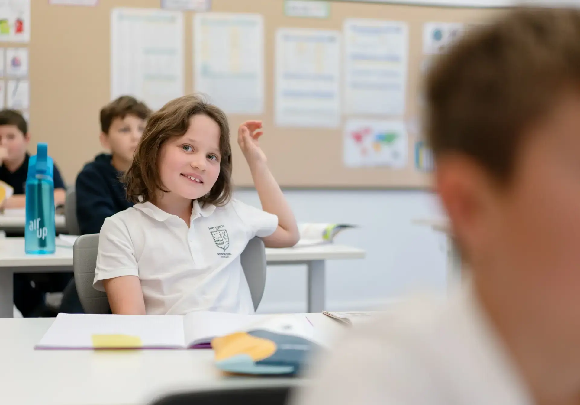 Student raising her hand in class to ask a question