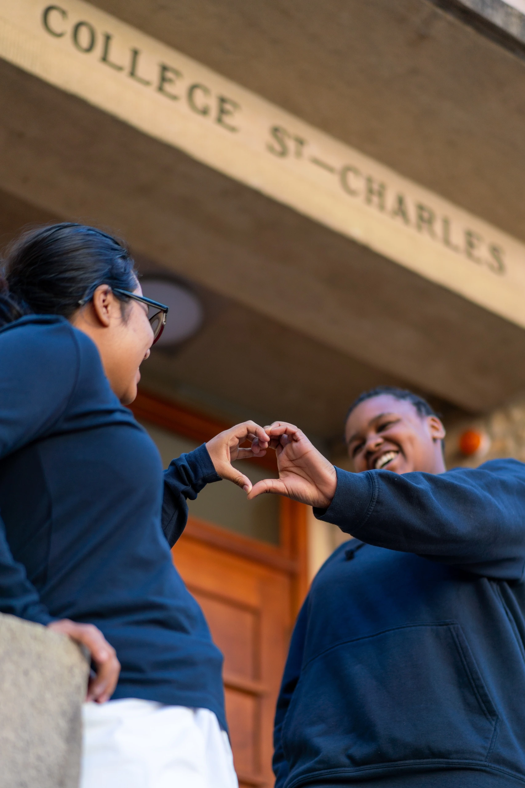 Two students making a heart with their hands
